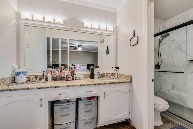 bathroom featuring crown molding, a shower with door, ceiling fan, vanity, and toilet