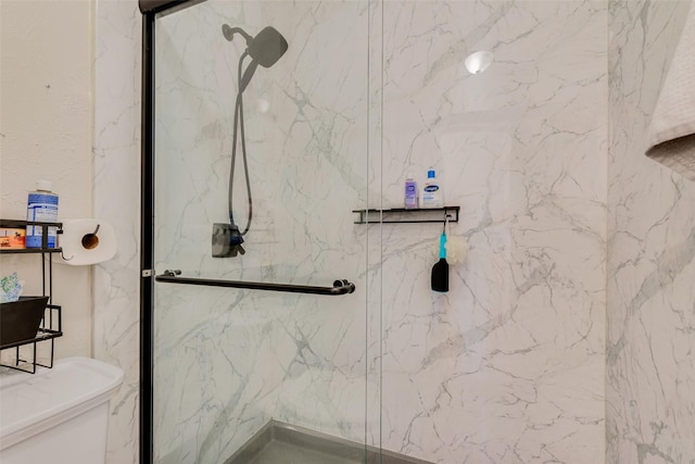 bathroom featuring a shower with shower door and toilet