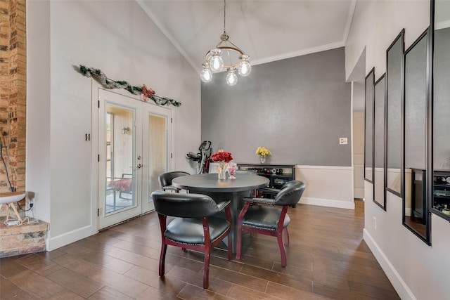 dining space with high vaulted ceiling, ornamental molding, a notable chandelier, dark wood-type flooring, and french doors