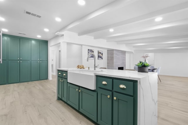 kitchen with a center island with sink, light hardwood / wood-style flooring, sink, and green cabinetry