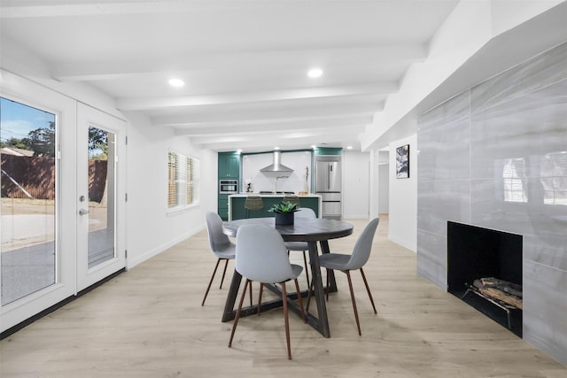 dining space with beam ceiling, light hardwood / wood-style floors, and french doors