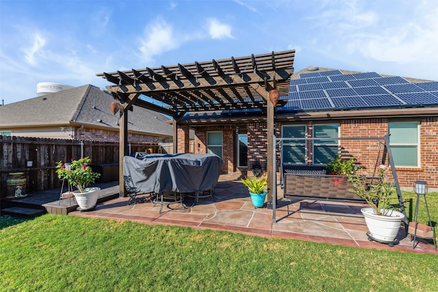 back of house with a pergola, a patio area, a yard, and solar panels