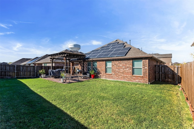 rear view of property featuring a pergola, a patio area, a lawn, and solar panels