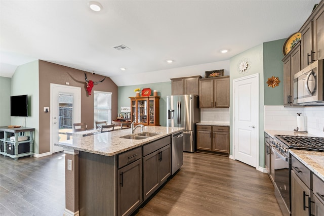 kitchen featuring sink, stainless steel appliances, dark hardwood / wood-style floors, lofted ceiling, and a center island with sink