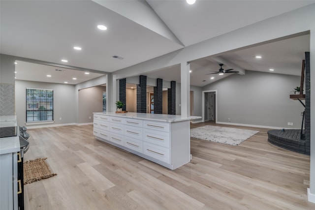 kitchen featuring light wood-type flooring, a center island, ceiling fan, vaulted ceiling with beams, and white cabinetry