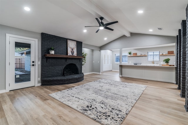 living room with a fireplace, light hardwood / wood-style flooring, and a wealth of natural light