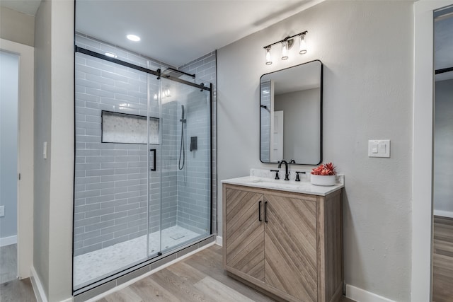 bathroom with hardwood / wood-style floors, vanity, and a shower with shower door