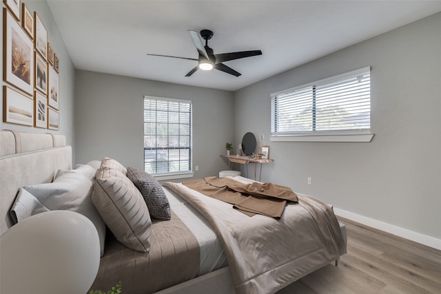 bedroom featuring light hardwood / wood-style flooring, multiple windows, and ceiling fan