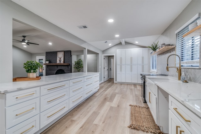 kitchen featuring white cabinetry, light stone counters, a fireplace, and light hardwood / wood-style floors