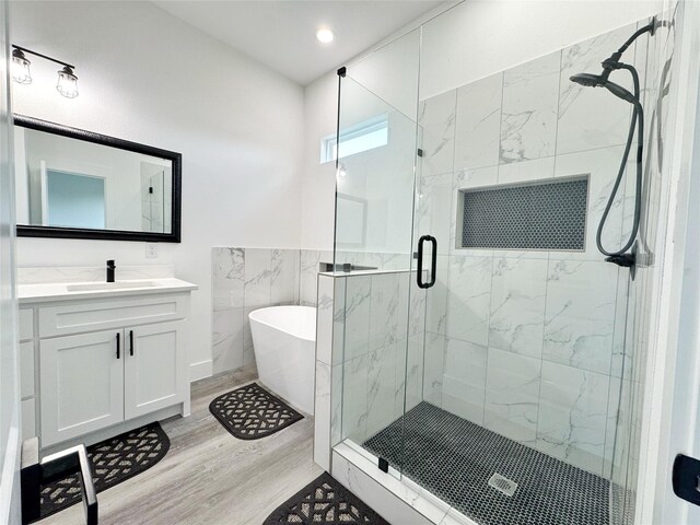 3210 Houston St, Greenville, TX 75401 - bathroom featuring wood finished floors, a stall shower, vanity, a soaking tub, and recessed lighting