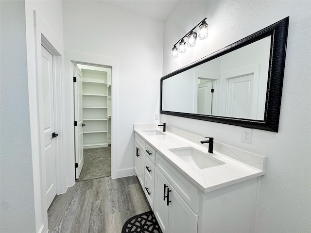 3210 Houston St, Greenville, TX 75401 - bathroom featuring baseboards, wood finished floors, a sink, and double vanity