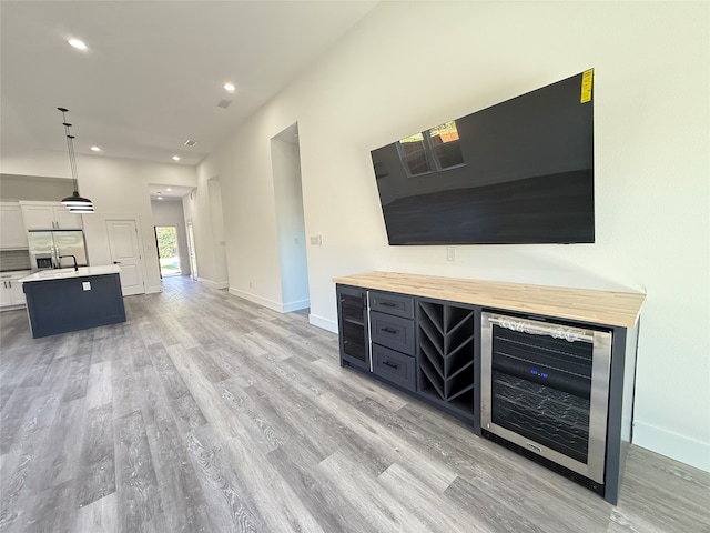 unfurnished living room with wine cooler, light hardwood / wood-style flooring, and sink