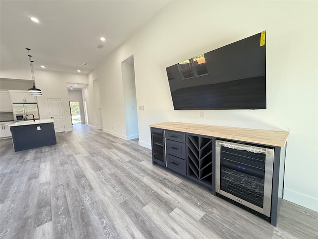 3210 Houston St, Greenville, TX 75401 - unfurnished living room featuring baseboards, light wood-style floors, and wine cooler