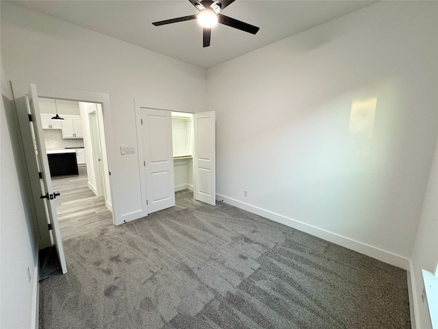 unfurnished bedroom featuring ceiling fan, light colored carpet, and a closet