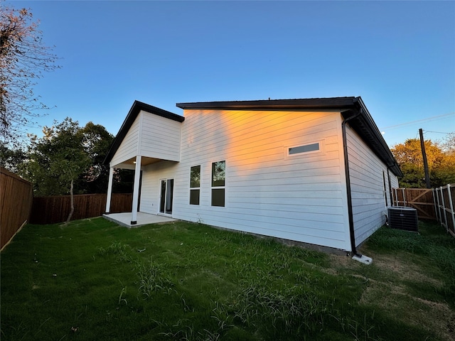 rear view of property with a lawn, cooling unit, and a patio