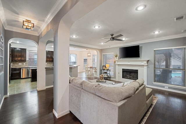 living room featuring crown molding, dark hardwood / wood-style floors, ceiling fan, and a fireplace