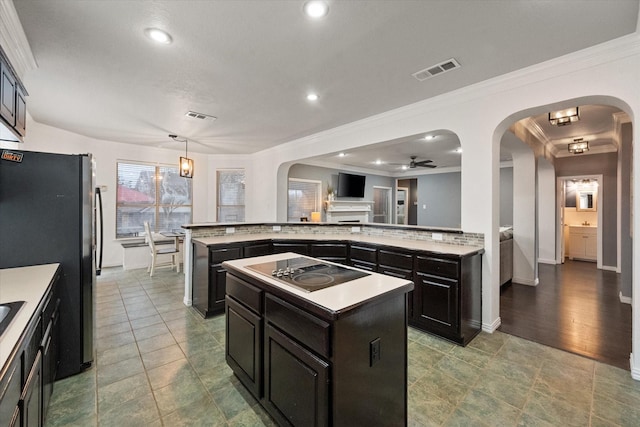 kitchen with pendant lighting, stainless steel fridge, a center island, ornamental molding, and black electric cooktop