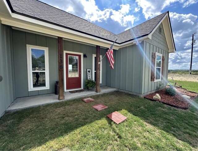 view of exterior entry featuring a porch and a lawn