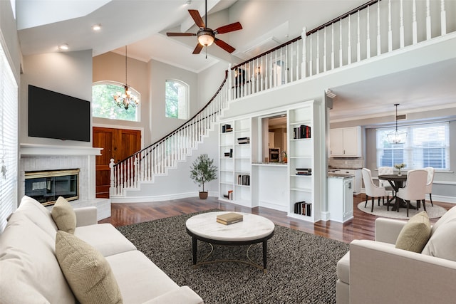 living room with a healthy amount of sunlight, dark wood-type flooring, a high ceiling, and a tiled fireplace