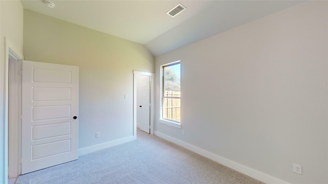 spare room with light colored carpet and vaulted ceiling