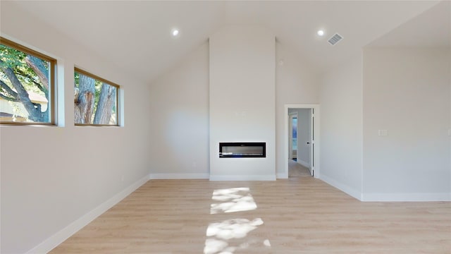 unfurnished living room featuring high vaulted ceiling and light hardwood / wood-style flooring