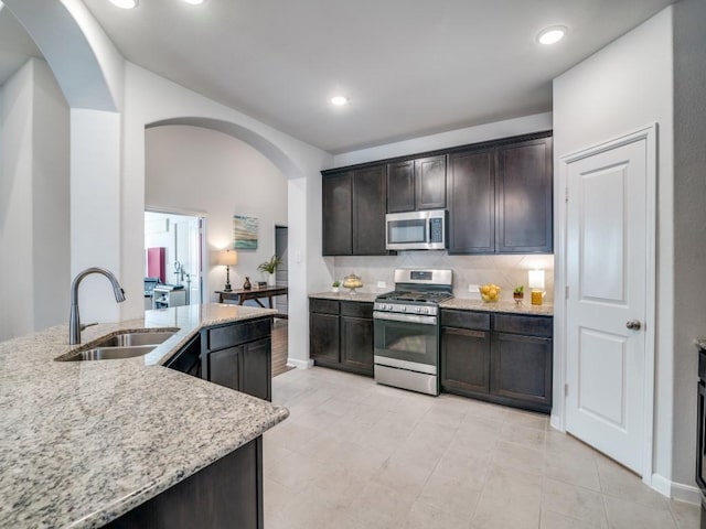1523 Green Meadows Way, Wylie, TX 75098 - kitchen with stainless steel appliances, a sink, arched walkways, decorative backsplash, and dark brown cabinets