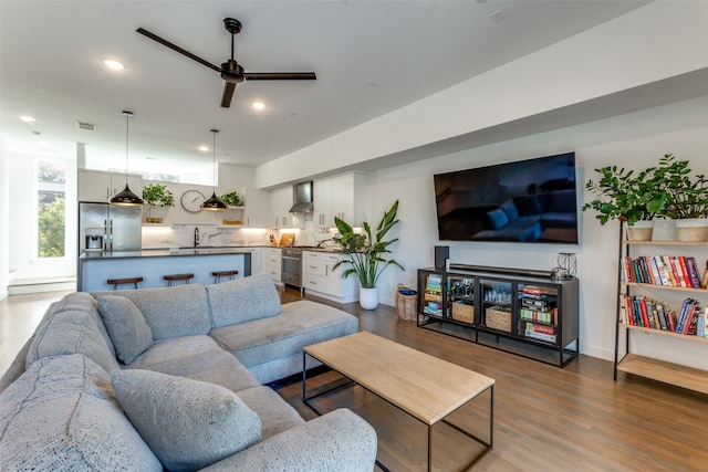 living room featuring ceiling fan, sink, and hardwood / wood-style flooring