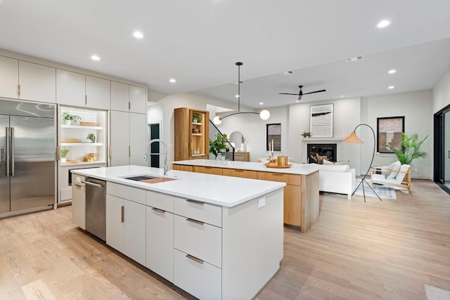 kitchen with ceiling fan, sink, a center island with sink, white cabinets, and appliances with stainless steel finishes