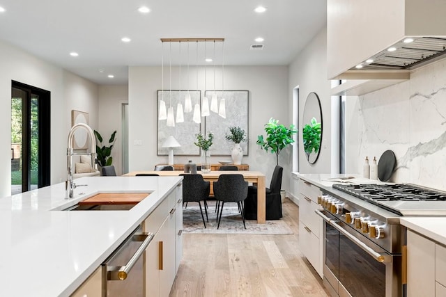 kitchen with white cabinetry, sink, pendant lighting, appliances with stainless steel finishes, and custom exhaust hood