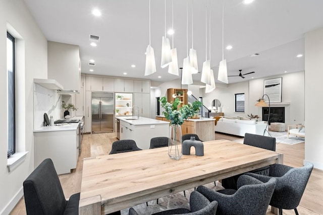 dining space with ceiling fan, sink, and light wood-type flooring