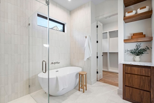 bathroom featuring separate shower and tub, tile patterned flooring, vanity, and tile walls