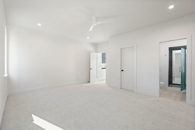 unfurnished bedroom with ceiling fan, ensuite bathroom, and light carpet