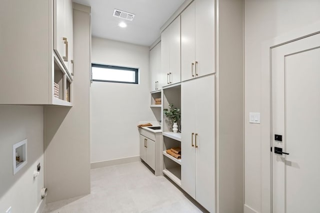 laundry room featuring electric dryer hookup, hookup for a washing machine, and cabinets