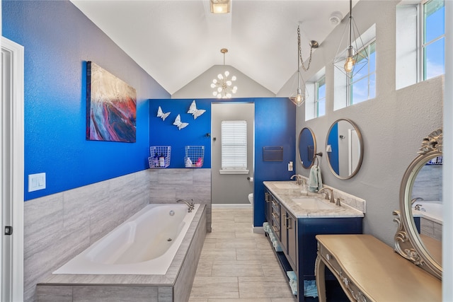 bathroom with vanity, toilet, tiled tub, and vaulted ceiling