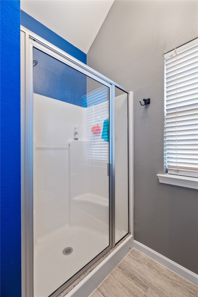 bathroom featuring plenty of natural light, wood-type flooring, and a shower with door