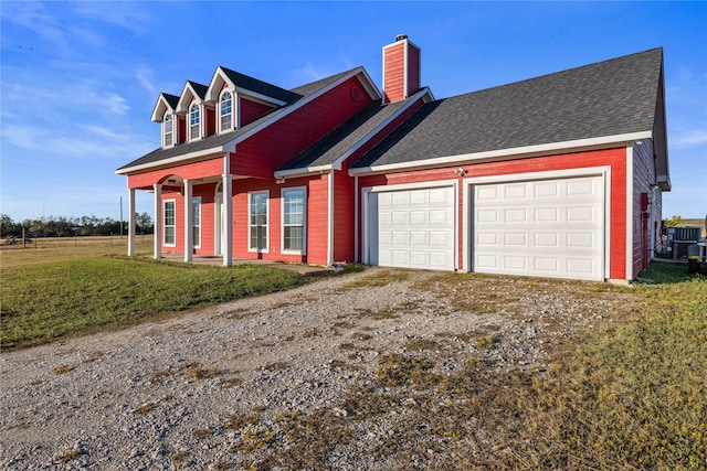 cape cod home featuring a garage and a front lawn