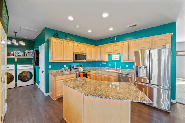 kitchen with washer and clothes dryer, a kitchen island, dark wood-type flooring, and appliances with stainless steel finishes