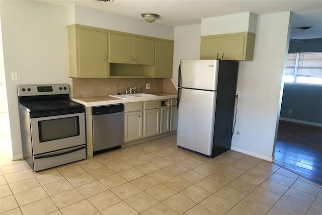 kitchen featuring sink, tasteful backsplash, tile countertops, light tile patterned floors, and appliances with stainless steel finishes