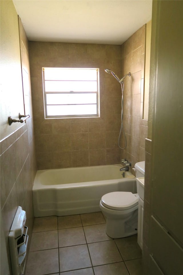 bathroom featuring tile patterned flooring, tiled shower / bath combo, and toilet