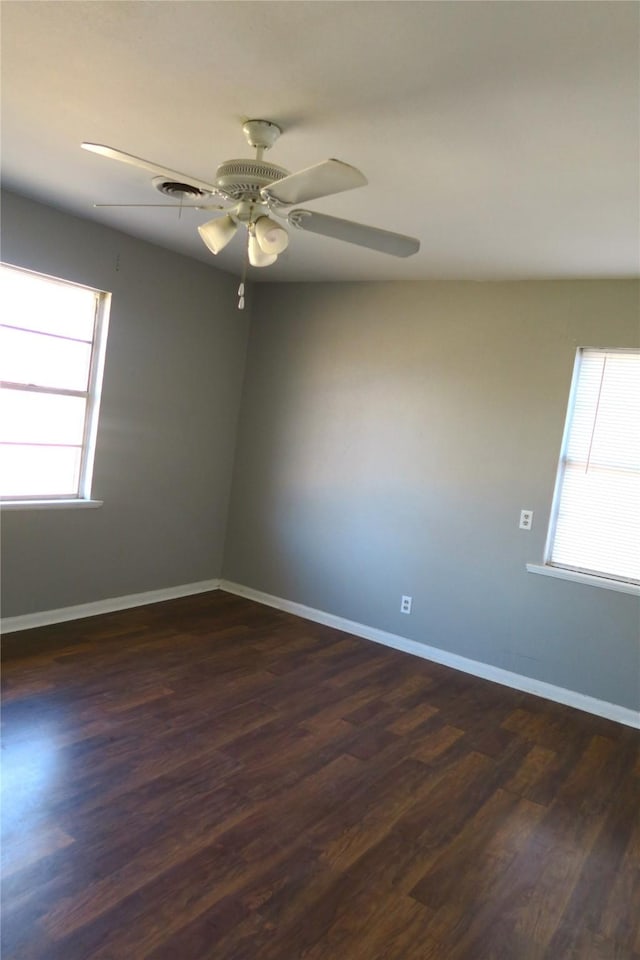 spare room featuring a wealth of natural light, ceiling fan, and dark hardwood / wood-style floors