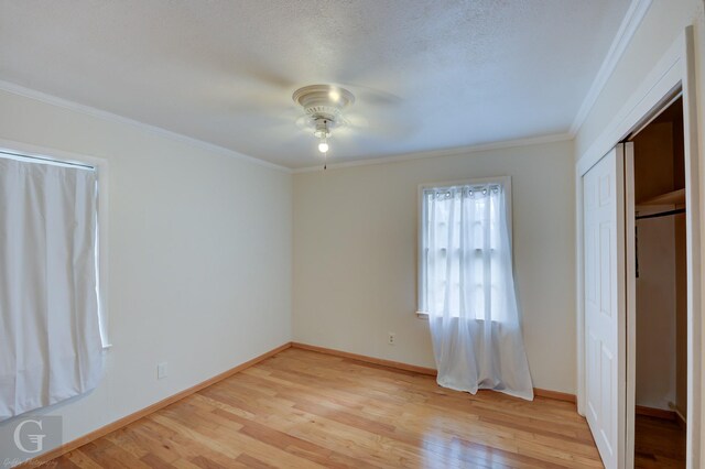 unfurnished bedroom featuring ceiling fan, crown molding, light hardwood / wood-style floors, a textured ceiling, and a closet