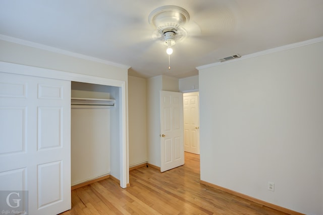 unfurnished bedroom featuring ceiling fan, light hardwood / wood-style floors, ornamental molding, and a closet