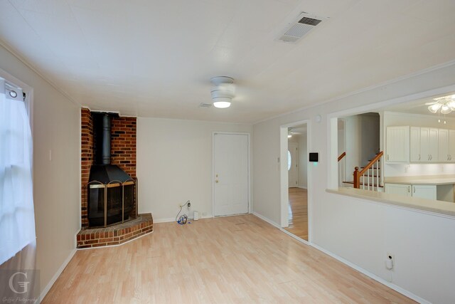 unfurnished living room with a wood stove and light wood-type flooring