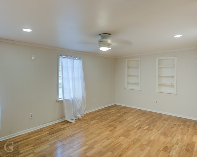 spare room with built in shelves, crown molding, and light wood-type flooring