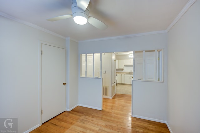 unfurnished room with crown molding, sink, ceiling fan, and light wood-type flooring