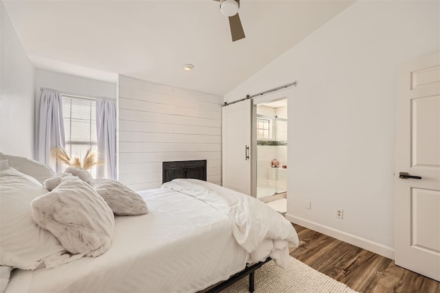 bedroom featuring ensuite bath, ceiling fan, a barn door, hardwood / wood-style flooring, and lofted ceiling