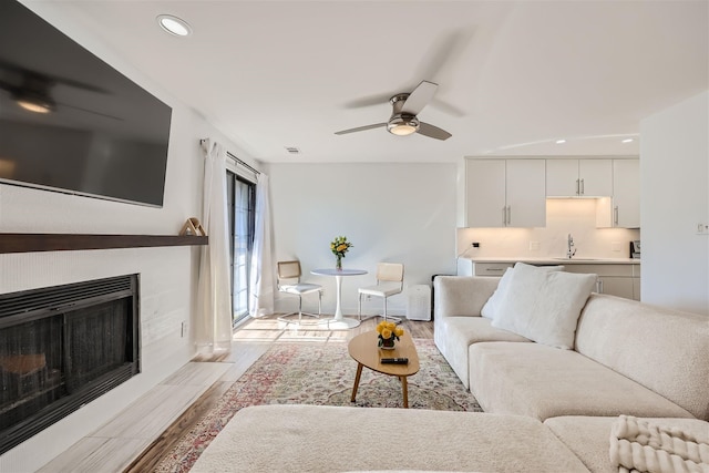 living room featuring ceiling fan, sink, and light hardwood / wood-style flooring