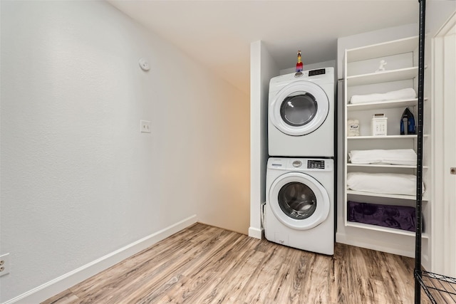 laundry room with wood-type flooring and stacked washer / dryer