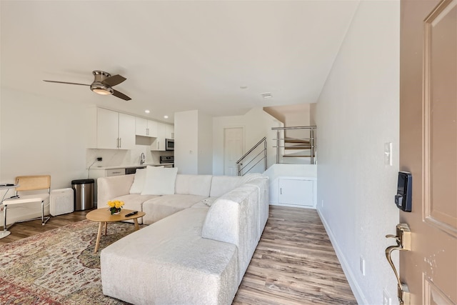 living room featuring ceiling fan, sink, and light hardwood / wood-style floors