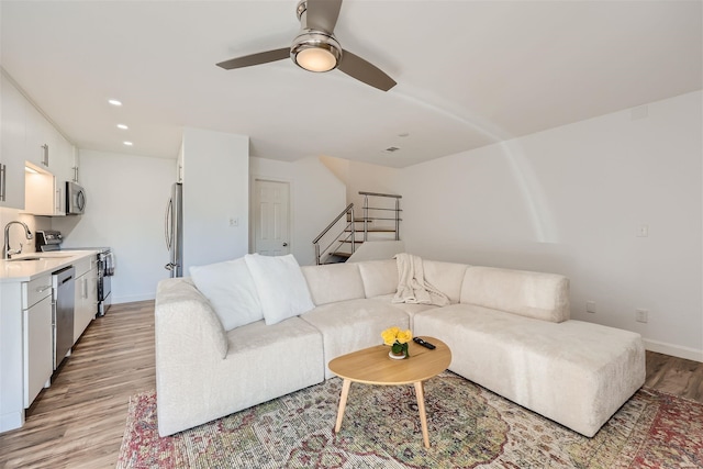 living room featuring light hardwood / wood-style flooring, ceiling fan, and sink